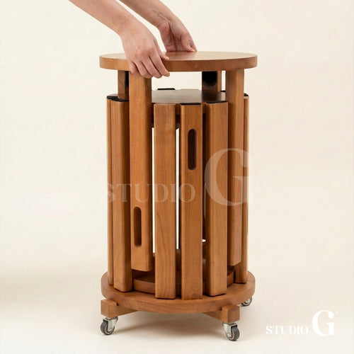 Hands lifting the top off the solid wood side table, showing the stools nested inside on the caster base
